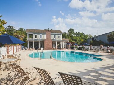 pool with chairs around it and a house in the background