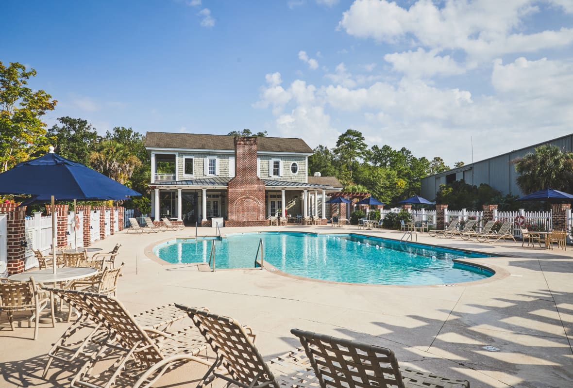 pool with chairs around it and a house in the background
