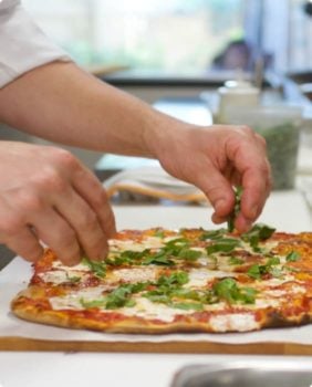 hands assembling pizza