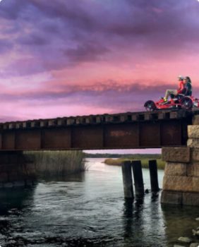 two people riding in a two person bike on a railway at sunset