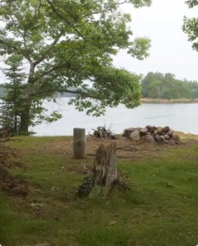 grass and fire pit with body of water in the background