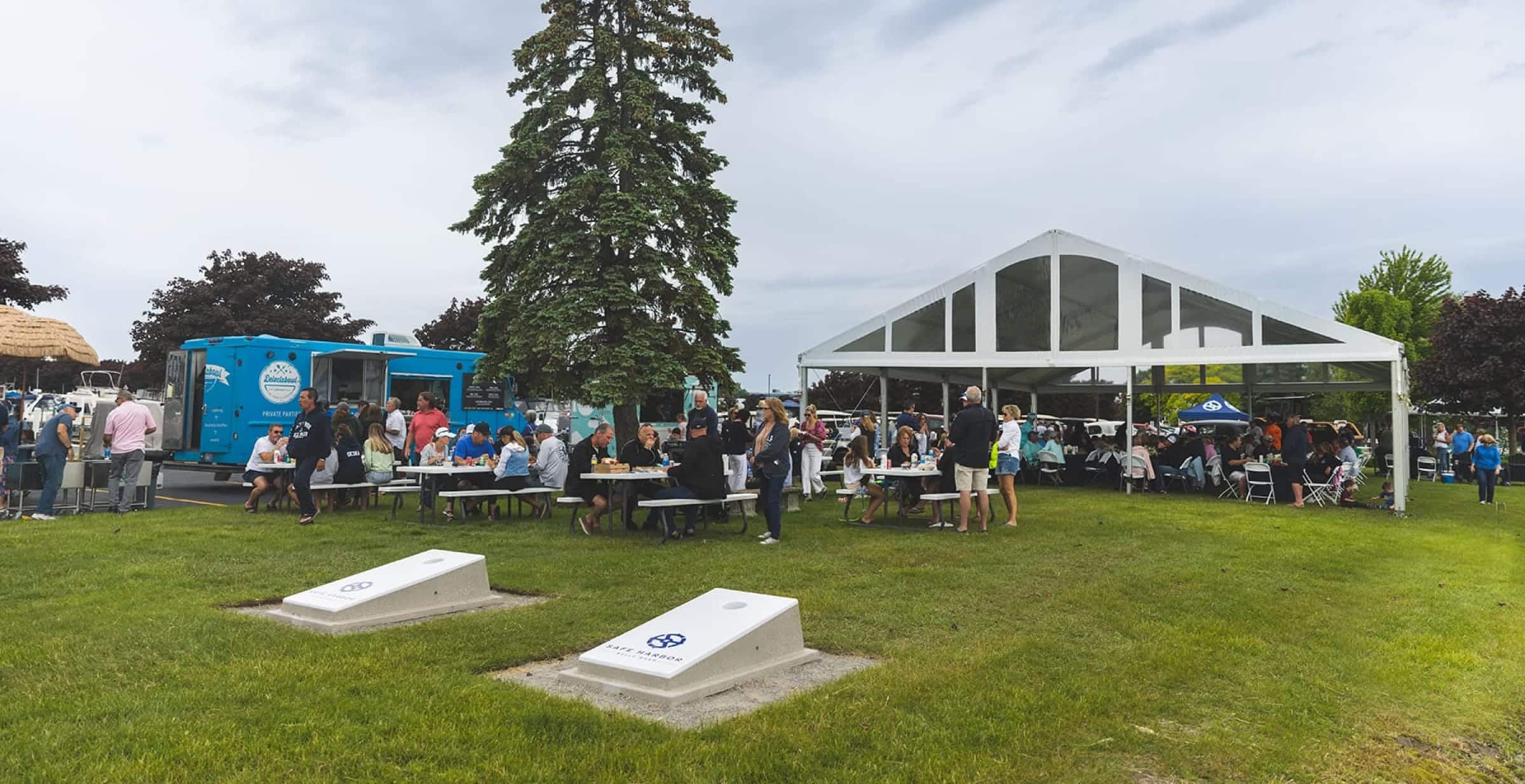 des gens lors d'un événement sur une pelouse verte, en train de jouer au cornhole