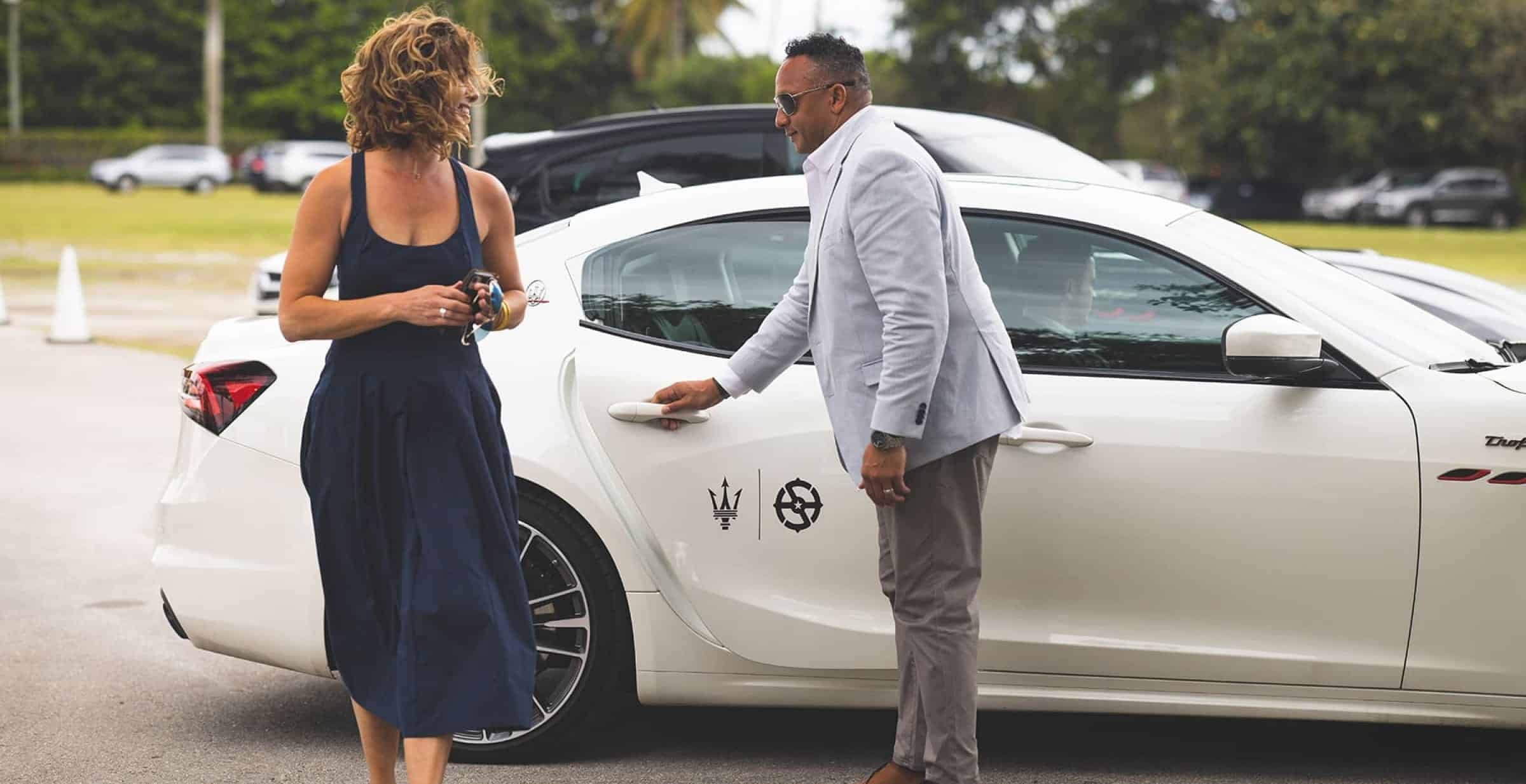 Un homme ferme la portière d'une voiture pour une femme qui vient d'en sortir