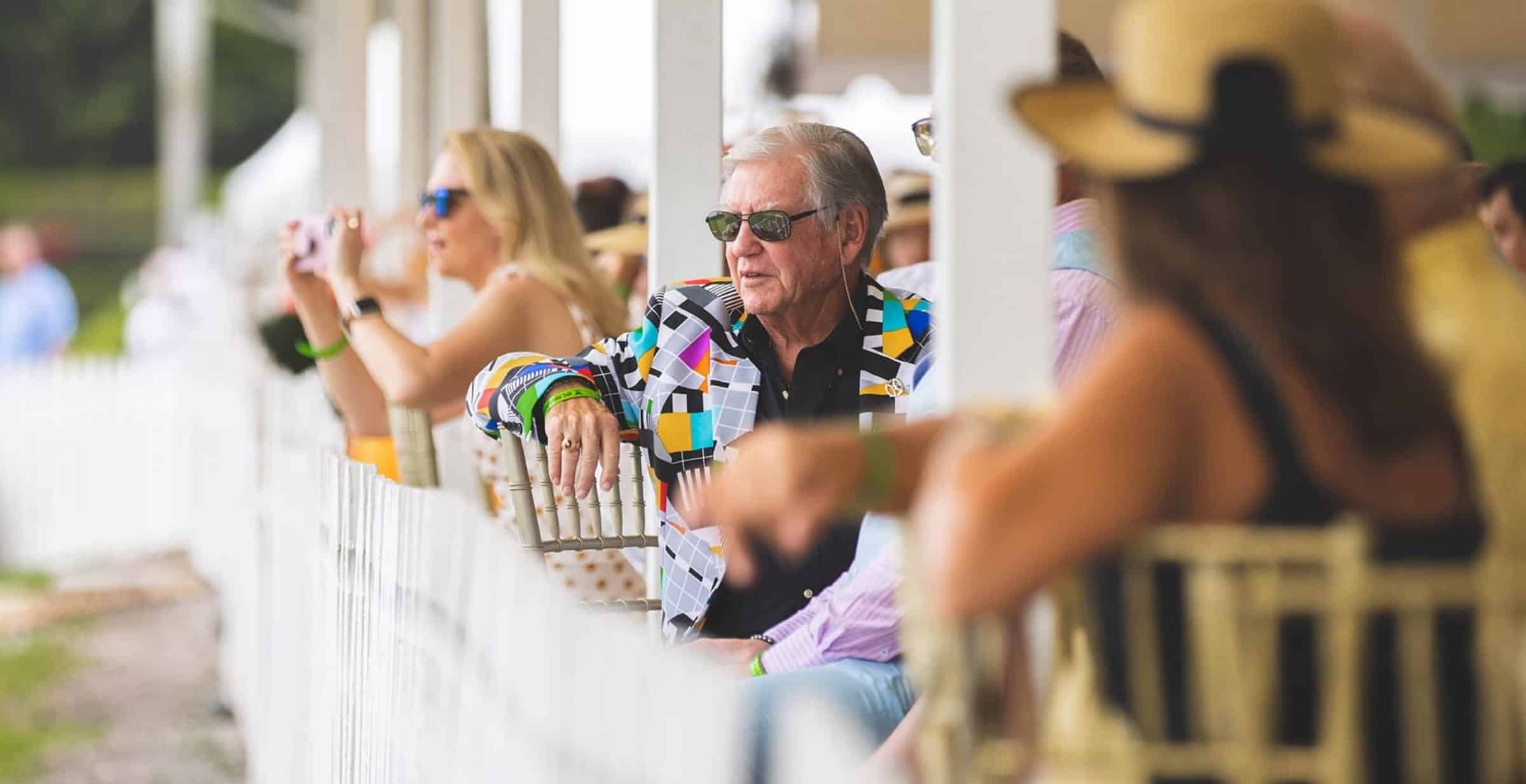 Un homme en costume aux couleurs vives qui assiste à un match de polo