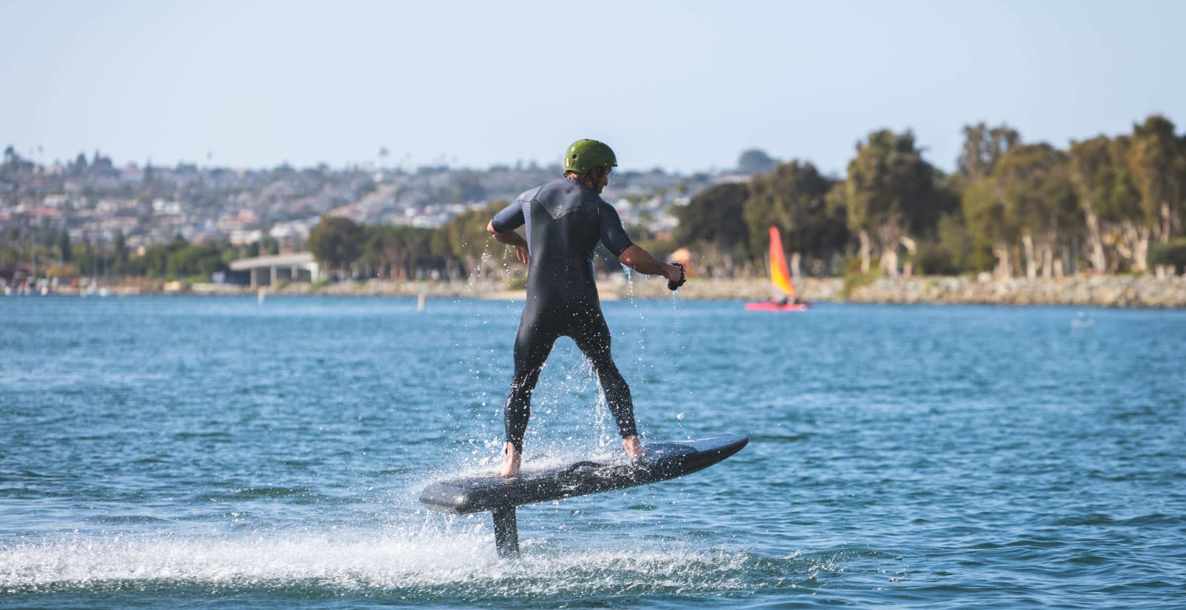 Un homme faisant du surf sur une planche électrique, coiffé d'un casque vert