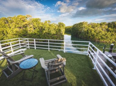 two chairs with a white fence around it looking out to water