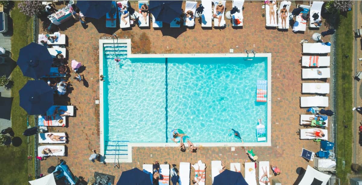 una piscina con mucha gente alrededor, sentada en las tumbonas