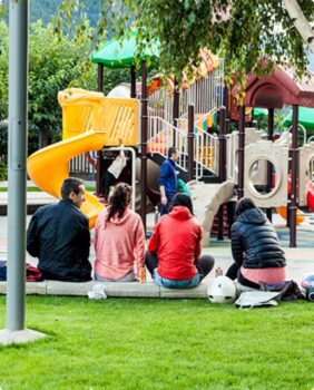 4 parents watching their children play on a playground