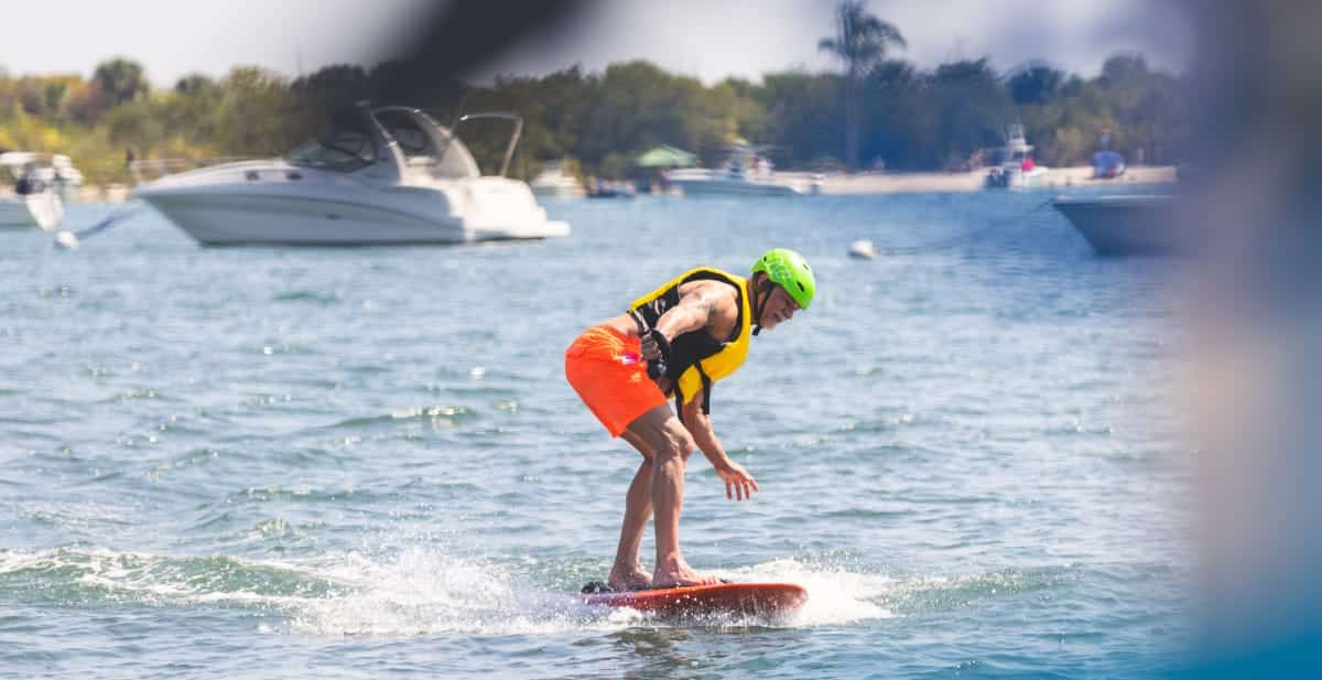 un hombre haciendo surf con pantalones cortos naranjas